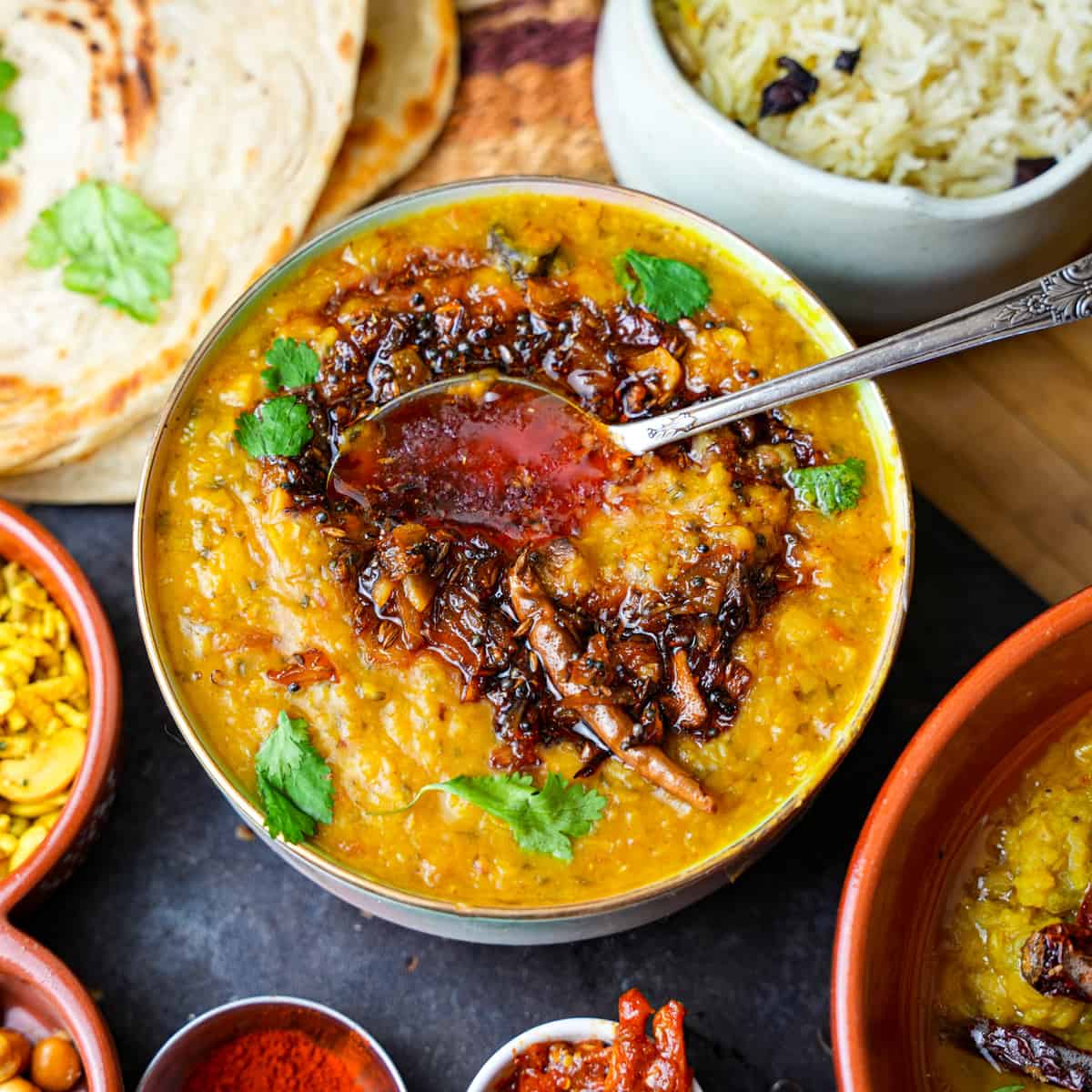 Arhar Dal with spoon. Roti, rice and condiments on the side.